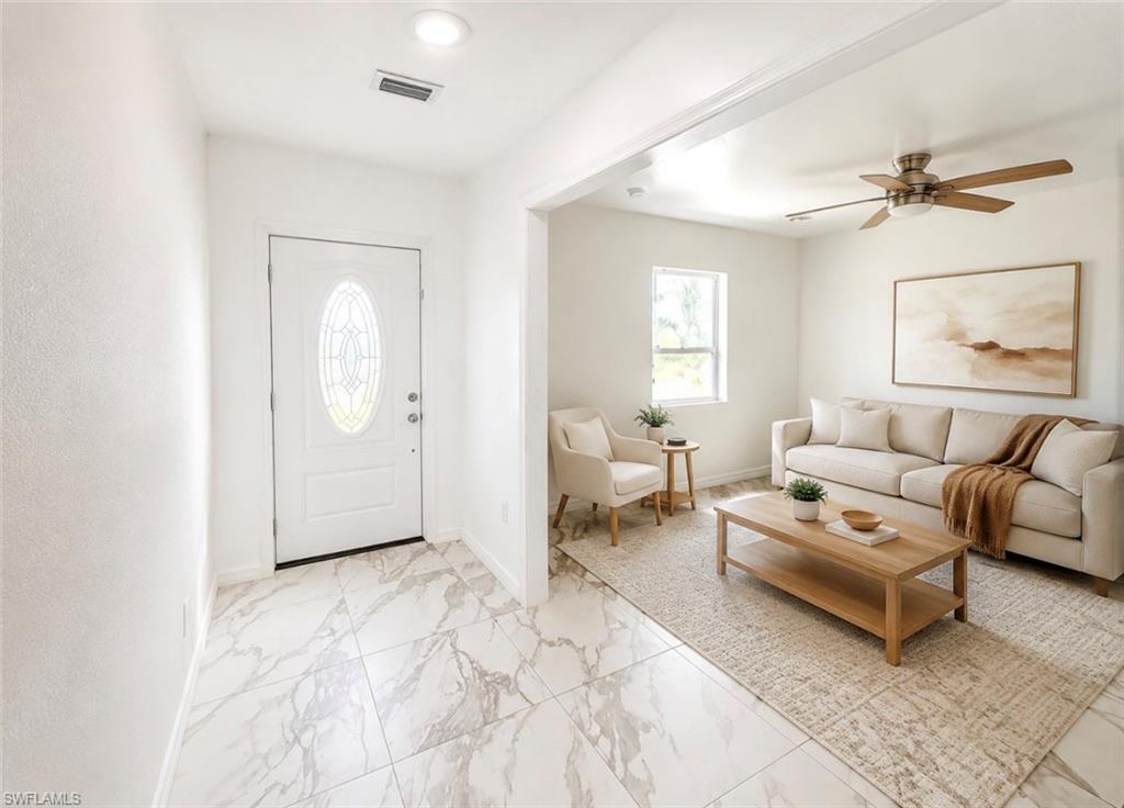 Entryway featuring large format marble-look tile flooring and a decorative oval glass front door