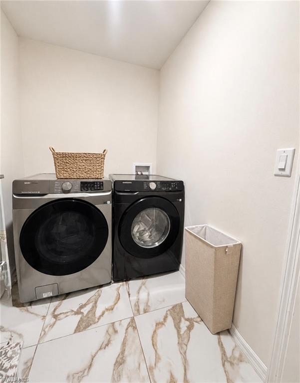Laundry area featuring durable tile flooring, light-toned walls, and a front-loading washer and dryer