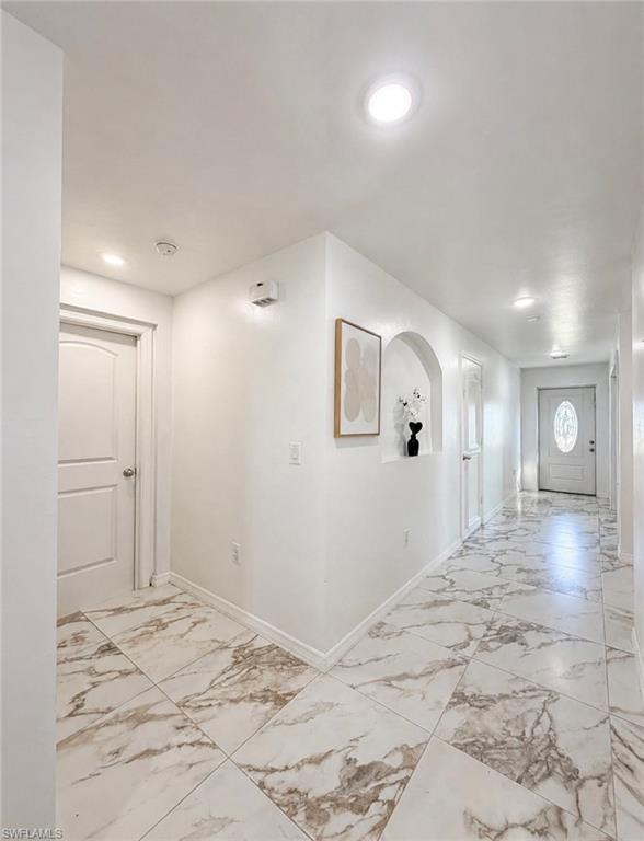 Recessed lighting, arched wall niche, white interior doors, and patterned tile flooring
