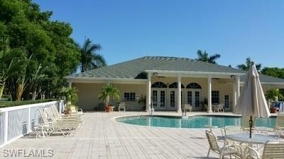 Expansive resort-style outdoor living space featuring a resort-style swimming pool with sun deck, generous paver patio, covered loggia with arched openings, mature tropical landscaping including palm trees, and multiple seating areas for entertaining