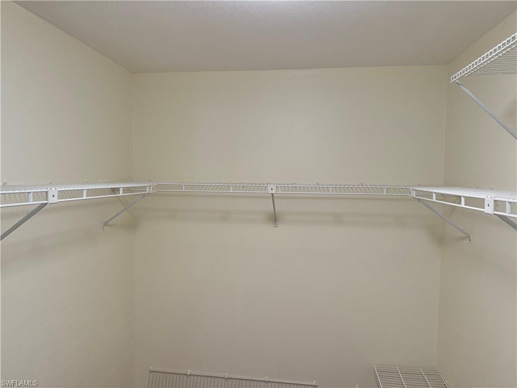 Spacious walk-in closet featuring wire shelving systems with multiple storage levels and clean, neutral walls ideal for organized wardrobe storage