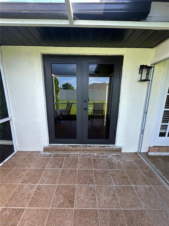 Modern French doors with dual glass panels open to a spacious patio featuring geometric tile flooring in warm earth tones