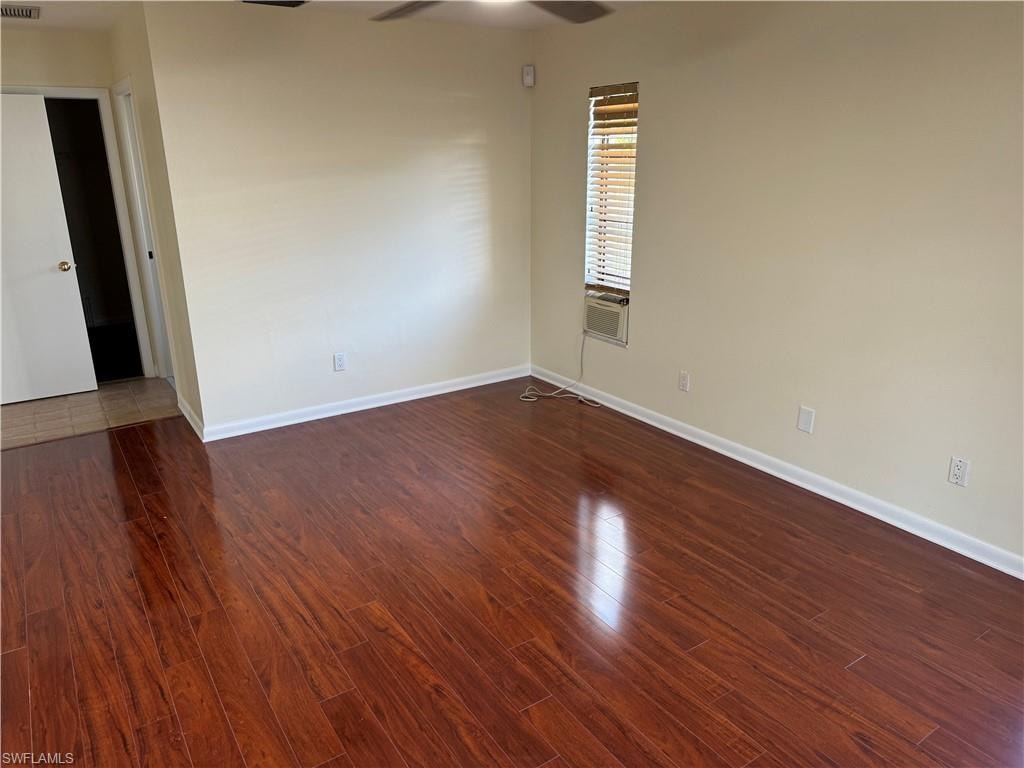 Room featuring wood-finish flooring, neutral wall paint, and a window with blinds