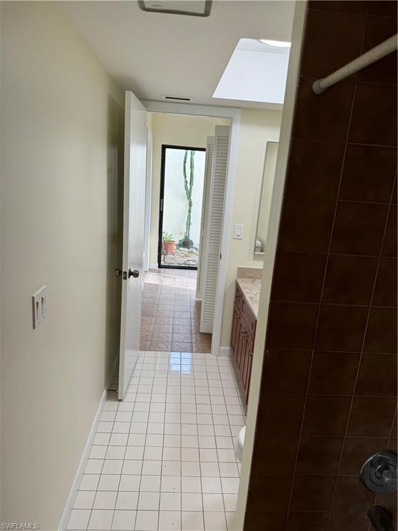 Bright hallway featuring white tile flooring, recessed ceiling lighting, and neutral wall finishes