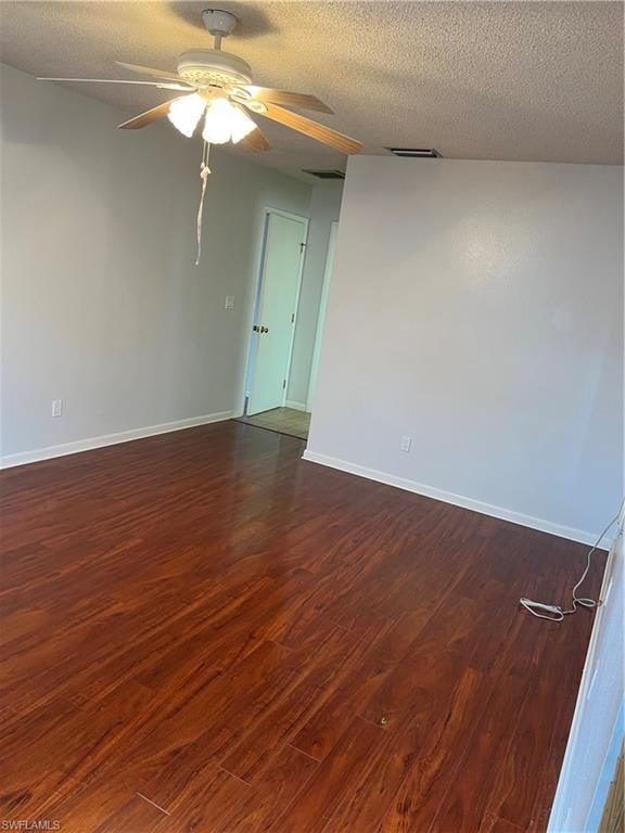 Spacious room featuring warm wood-finish flooring, ceiling fan with integrated lighting, and fresh white wall surfaces