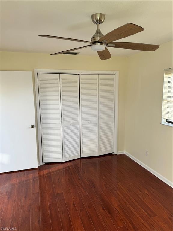 Spacious bedroom showcasing rich wood-finish flooring, fresh neutral walls, and abundant natural light from dual windows
