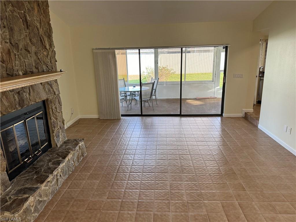 Living area featuring a stone-clad fireplace with a hearth, tile flooring, and sliding glass doors opening to a screened-in patio