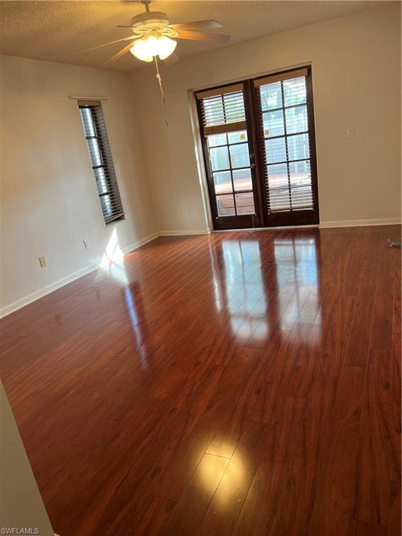 Spacious room featuring wood-finish flooring, a ceiling fan with integrated lighting, and French patio doors with blinds