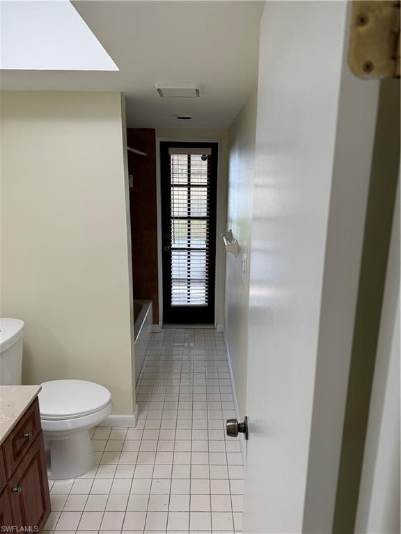 Galley-style bathroom featuring ceramic tile flooring, white wall finishes, and a dark wood vanity with integrated sink