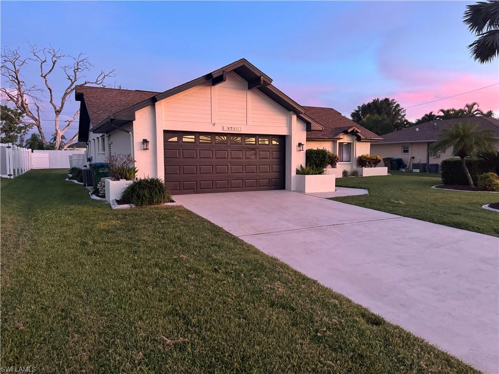 Charming single-story residence featuring a two-car garage with wood-finish doors, concrete driveway, and manicured front lawn
