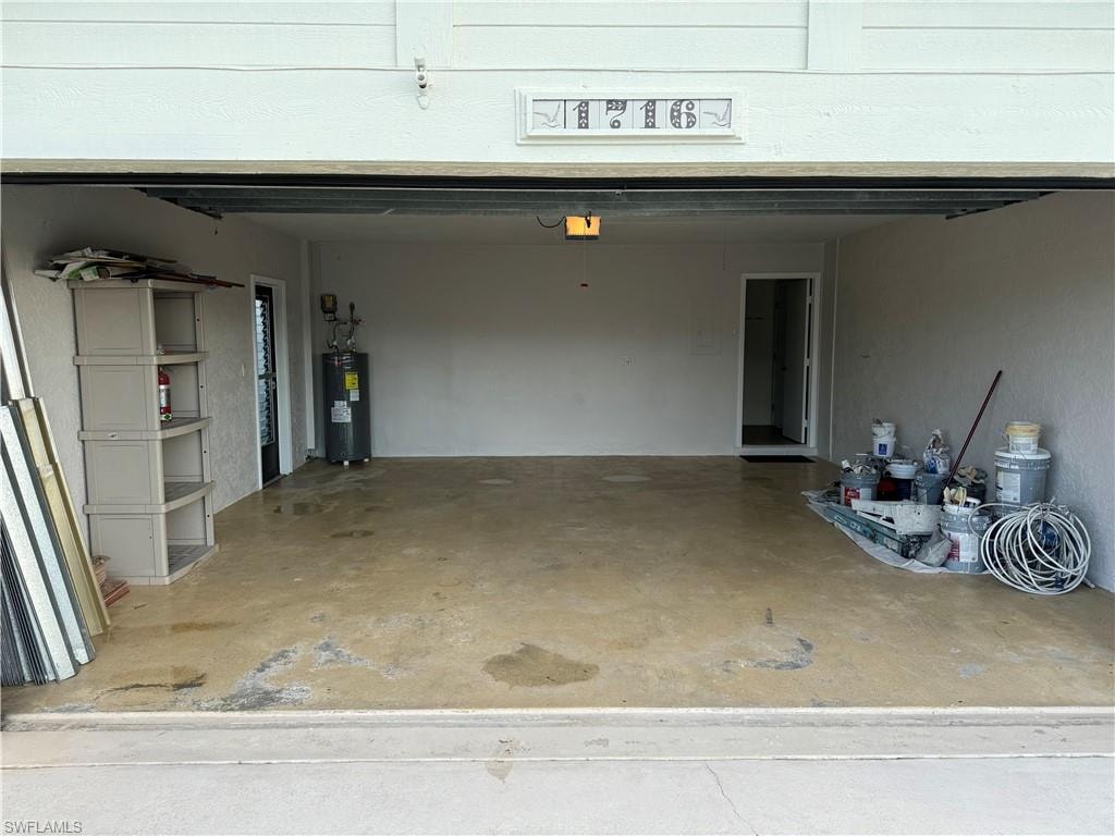 Spacious garage featuring concrete flooring, overhead garage door with automatic opener, wall-mounted storage shelving, and ample space for vehicles and equipment storage