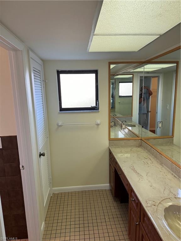 Master bathroom featuring a dual-sink vanity with marble-finish countertop, wood cabinetry, and large mirror with wood framing