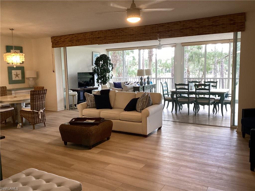 Living room featuring light wood-type flooring, a chandelier, and a ceiling fan