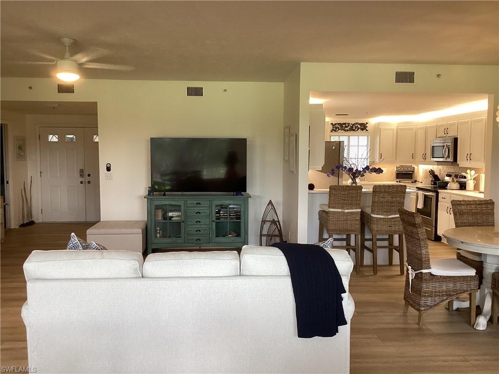 Living area featuring light wood finished floors and a ceiling fan