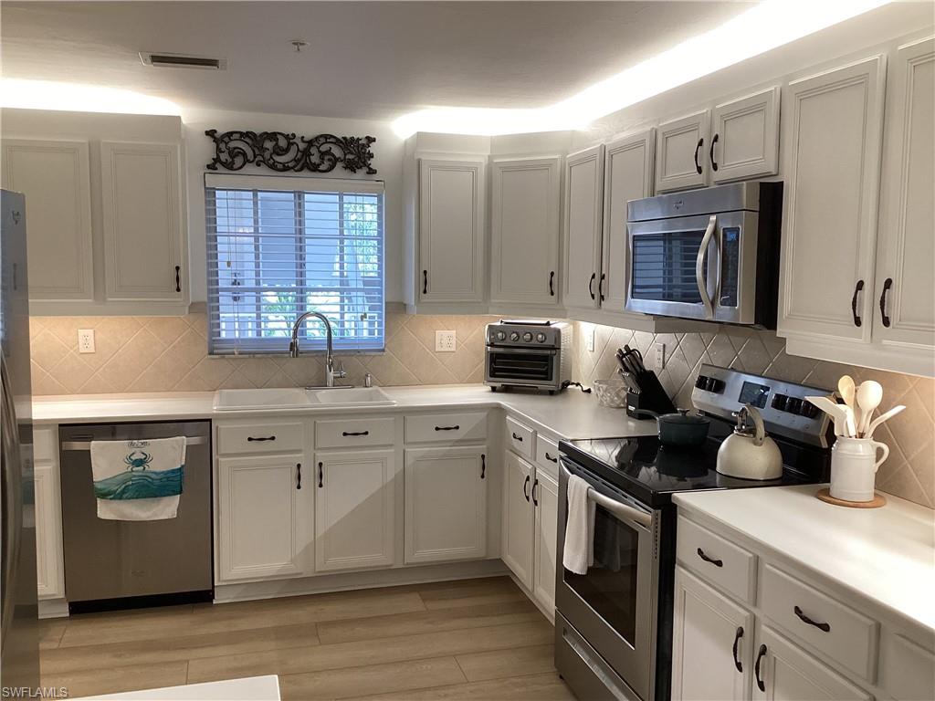 Kitchen featuring appliances with stainless steel finishes, light countertops, decorative backsplash, and light wood finished floors