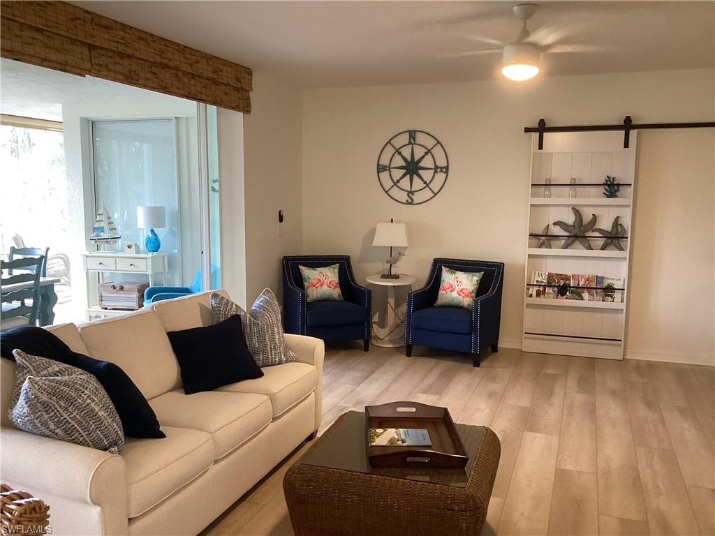 Living area with a barn door, wood finished floors, and ceiling fan