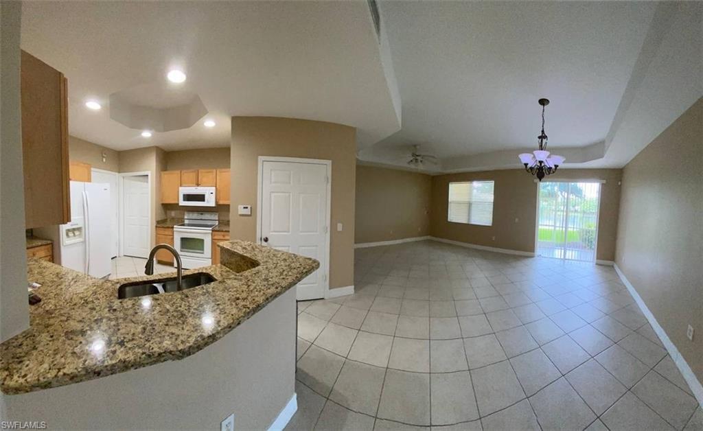Kitchen featuring granite countertops, wood cabinetry, and stainless steel sink with a gooseneck faucet