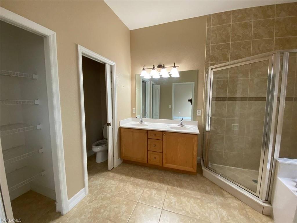 Bathroom featuring a dual vanity with a light wood-finish cabinet, white countertops, and a large mirror