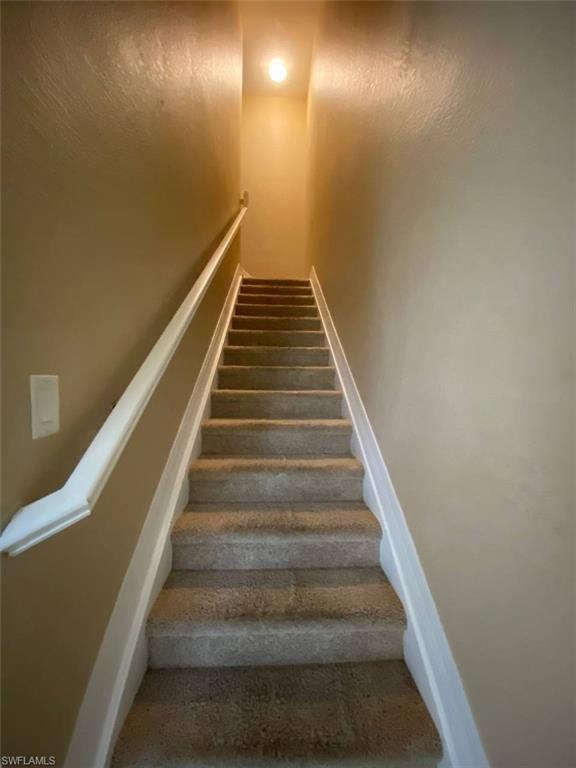 Carpeted staircase featuring a painted handrail and recessed ceiling light