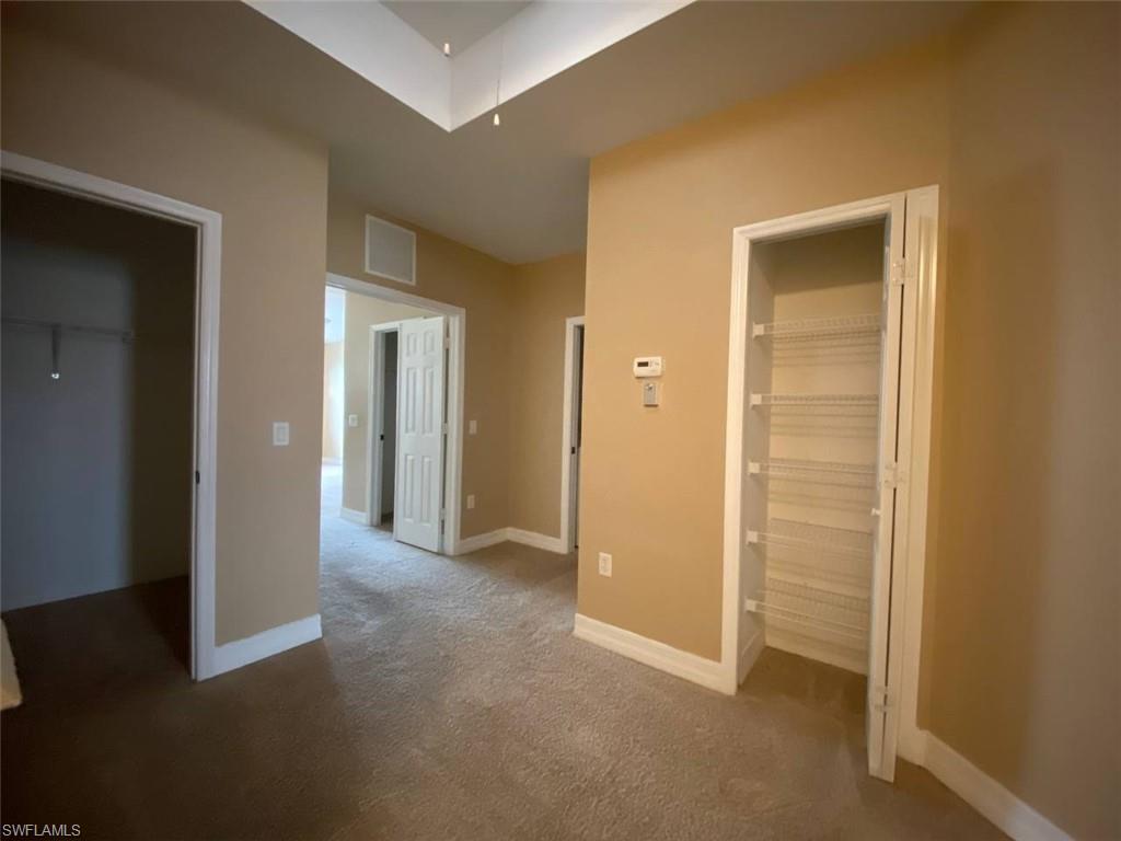 Interior hallway with neutral beige wall paint and matching carpet flooring