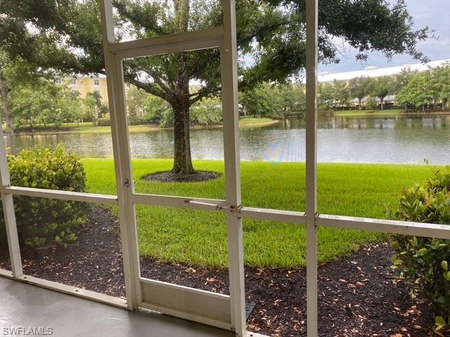 Screened patio overlooking a lake with lush landscaping and mature trees