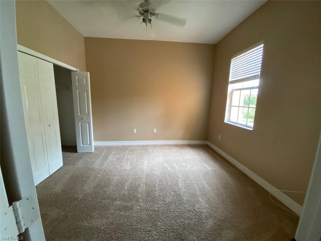 Carpeted room featuring a window with horizontal blinds, bi-fold closet doors, a white ceiling fan, and neutral wall paint