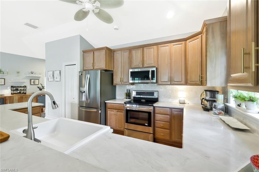 Modern kitchen featuring warm wood-finish cabinetry, white quartz countertops, and a large waterfall-edge island with seating