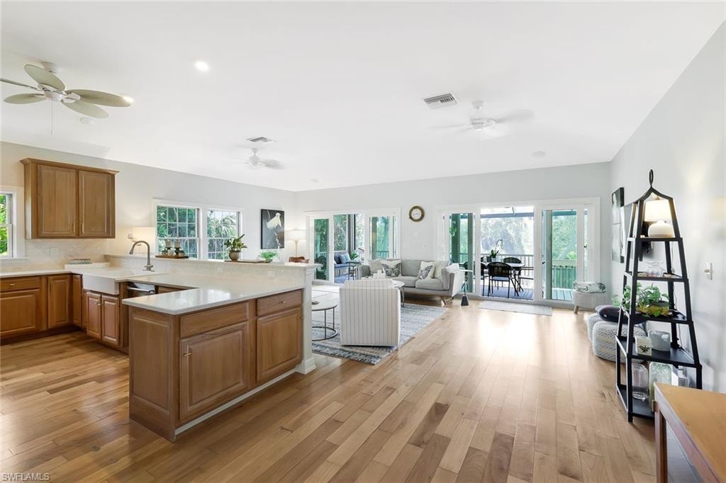 Open-concept living area featuring wood-finish flooring, a kitchen with light wood cabinetry and a farmhouse sink, and a spacious outdoor balcony accessed through sliding glass doors