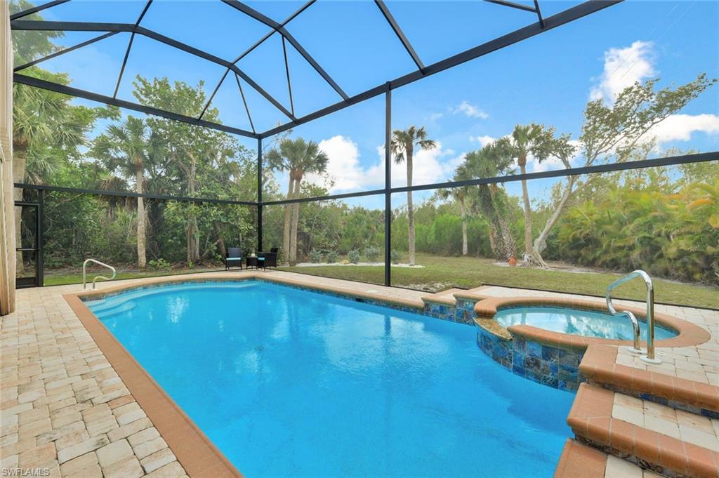 Resort-style saltwater pool with integrated spa, surrounded by a screened enclosure featuring aluminum framing and polycarbonate paneling