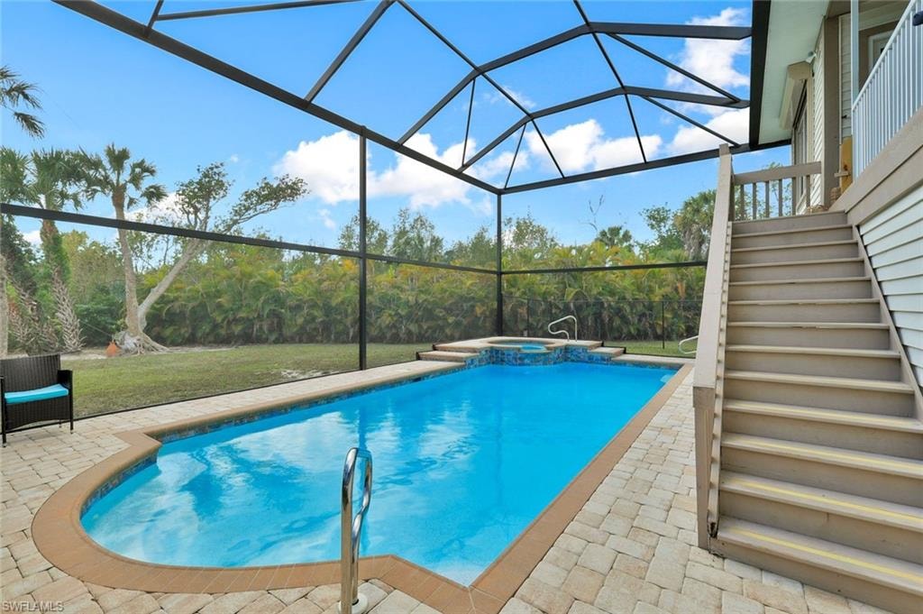 Screened pool enclosure featuring a rectangular pool, integrated spa, and paver decking