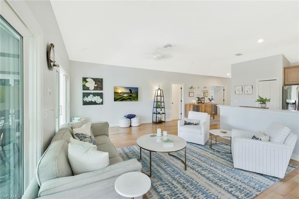 Spacious living area featuring wood-finish flooring, vaulted ceilings, and a ceiling fan