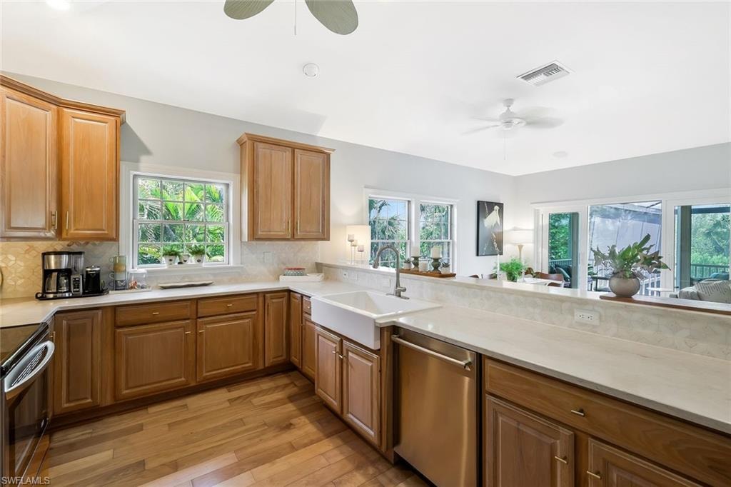 Chef's kitchen featuring warm wood cabinetry, a large farmhouse sink, and expansive quartz countertops with waterfall edge detailing