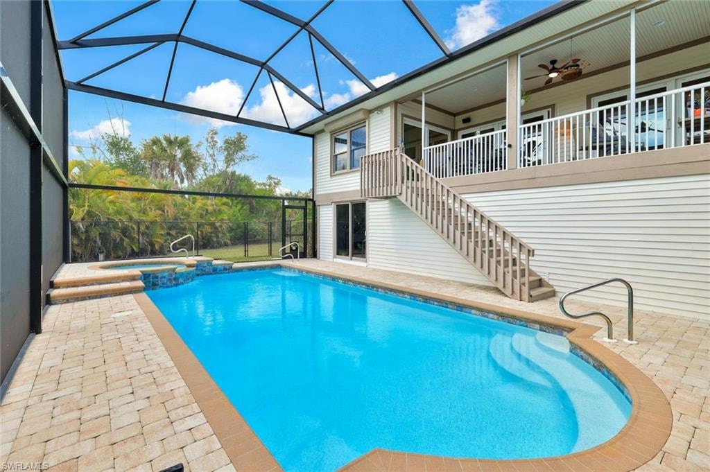 Resort-style saltwater pool with curved edges and sun shelf, enclosed by a black-framed screened lanai featuring a polycarbonate roof