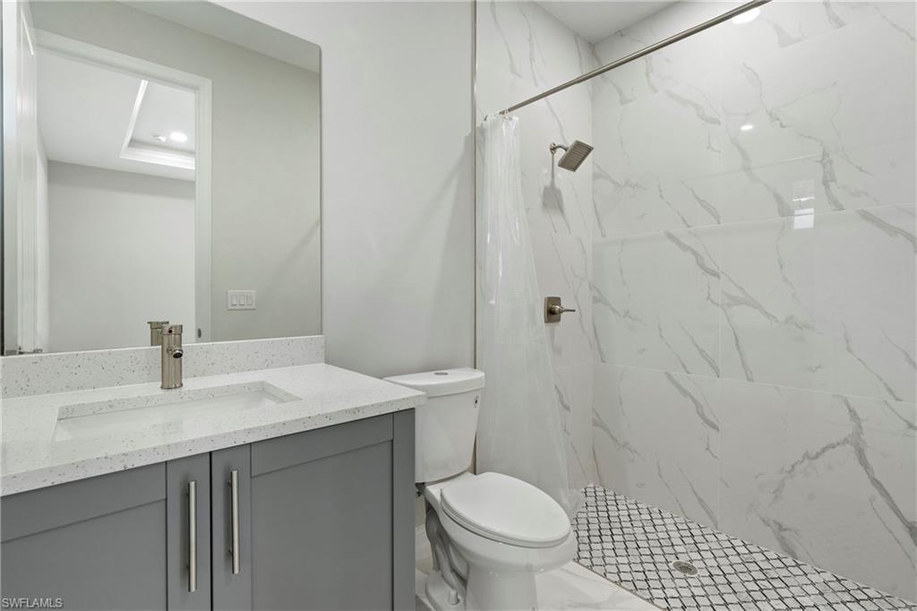 Full bath featuring toilet, marble finish floor, a shower stall, and vanity