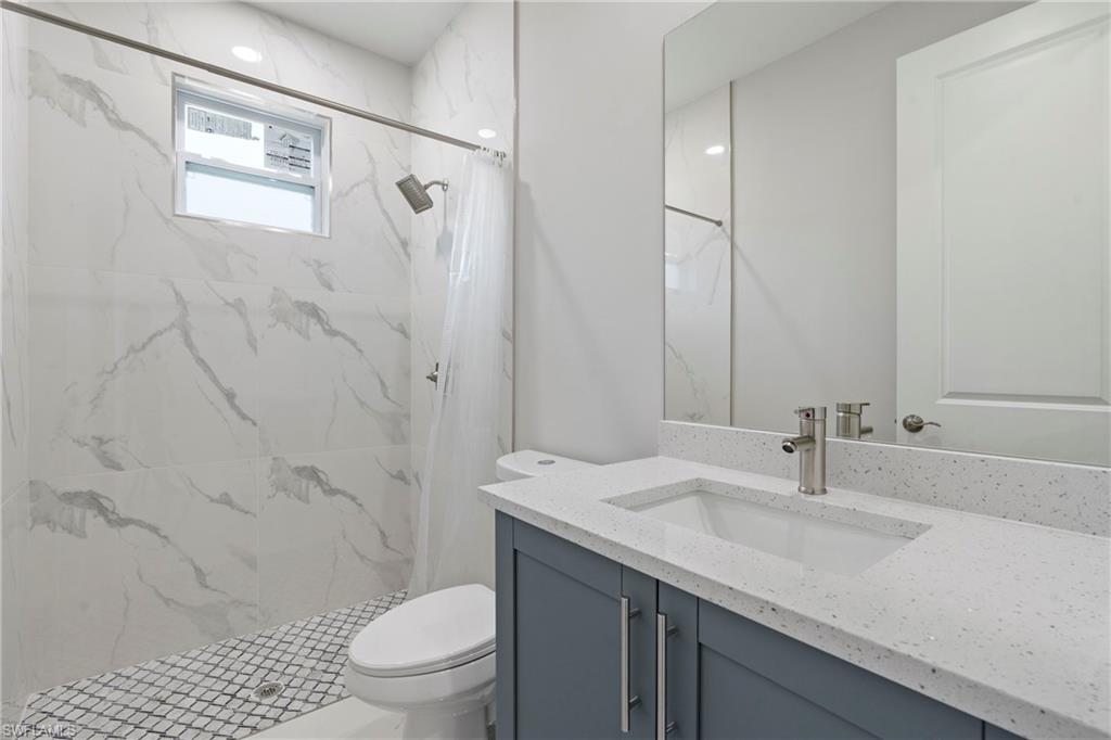 Full bathroom featuring vanity, a marble finish shower, and toilet
