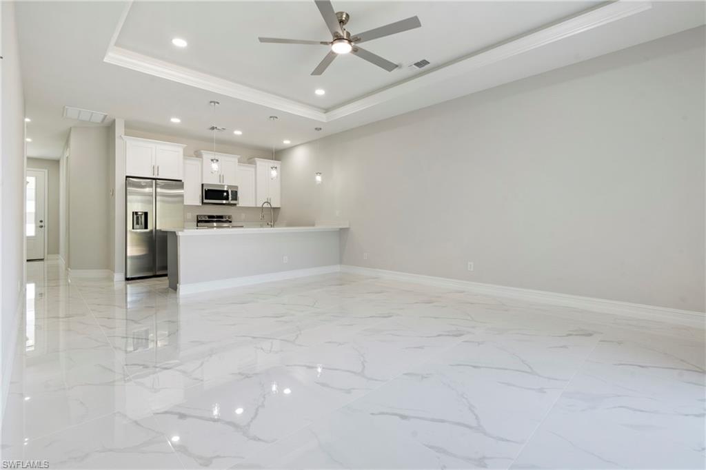 Unfurnished living room with marble finish floor, recessed lighting, a raised ceiling, visible vents, and a sink