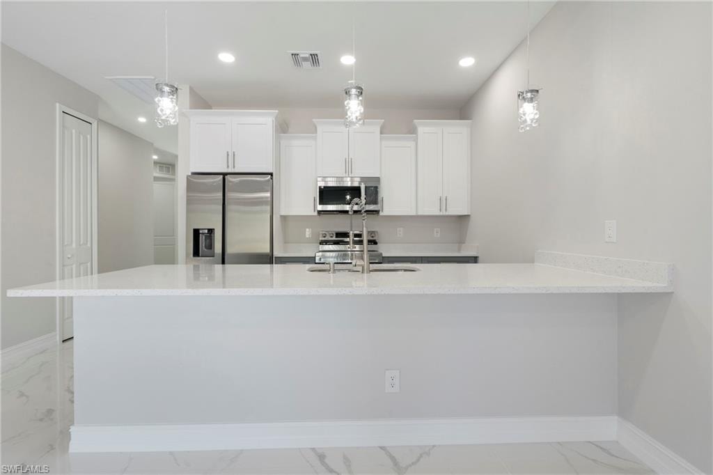 Kitchen with visible vents, appliances with stainless steel finishes, marble finish floor, white cabinetry, and a sink