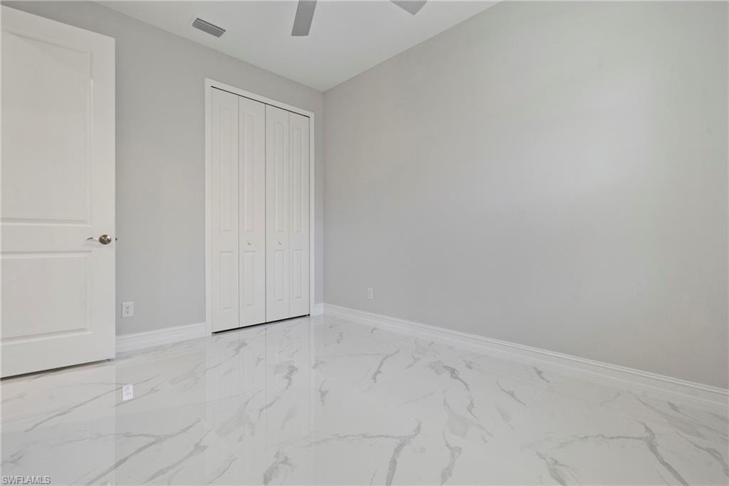 Unfurnished bedroom with a ceiling fan, visible vents, baseboards, marble finish floor, and a closet