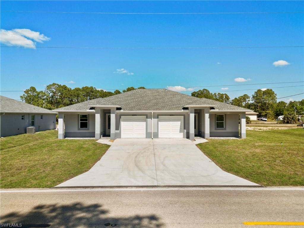 Prairie-style home with an attached garage, a front yard, concrete driveway, and stucco siding