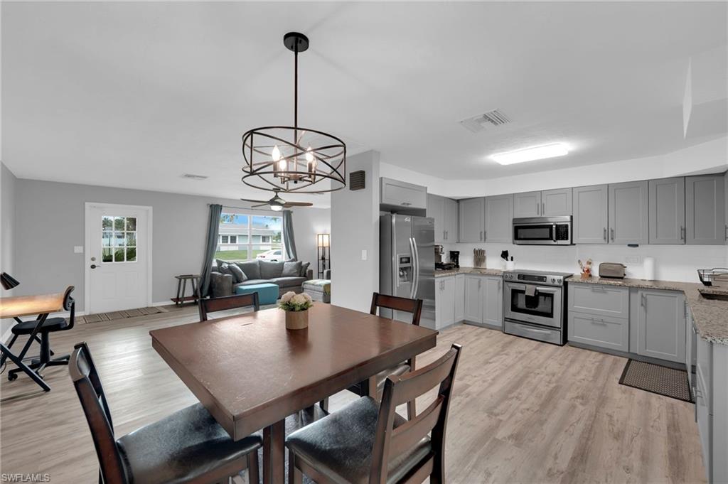 Open-concept living space featuring a modern kitchen with gray cabinetry, stainless steel appliances, and granite countertops