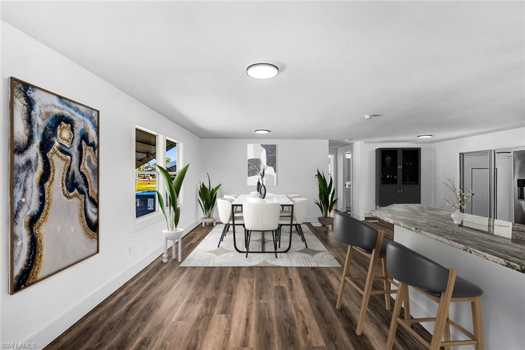 Open-concept dining and kitchen space featuring wood-finish flooring, recessed lighting, and a kitchen island with a stone-finish countertop