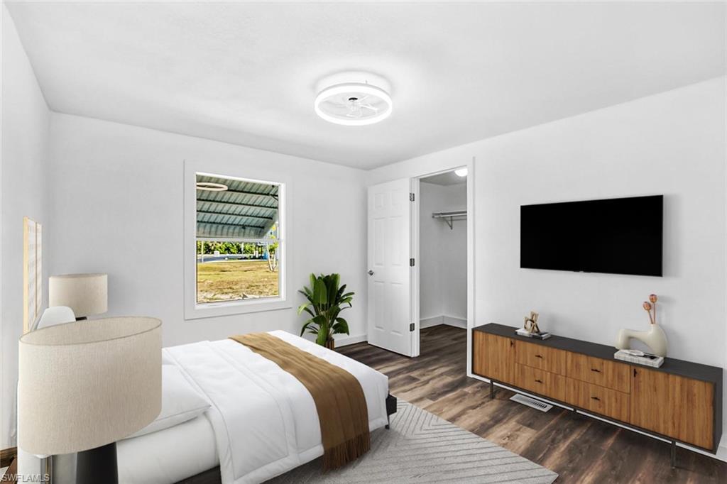 Modern bedroom featuring wood-finish flooring, recessed ceiling lighting, and a wall-mounted flat-screen television