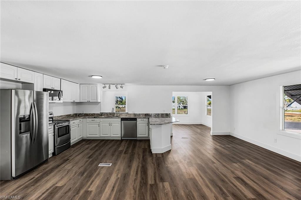 Spacious kitchen featuring white cabinetry, stainless steel appliances, granite countertops, and wood-finish flooring