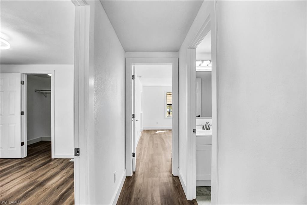 Hallway with wood-finish flooring and bright white walls