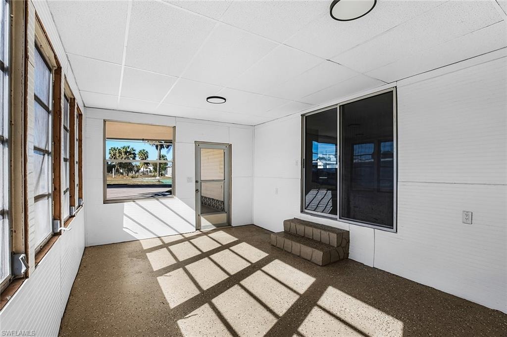 Enclosed sunroom featuring a textured ceiling, multiple window panels, and a full-light screen door