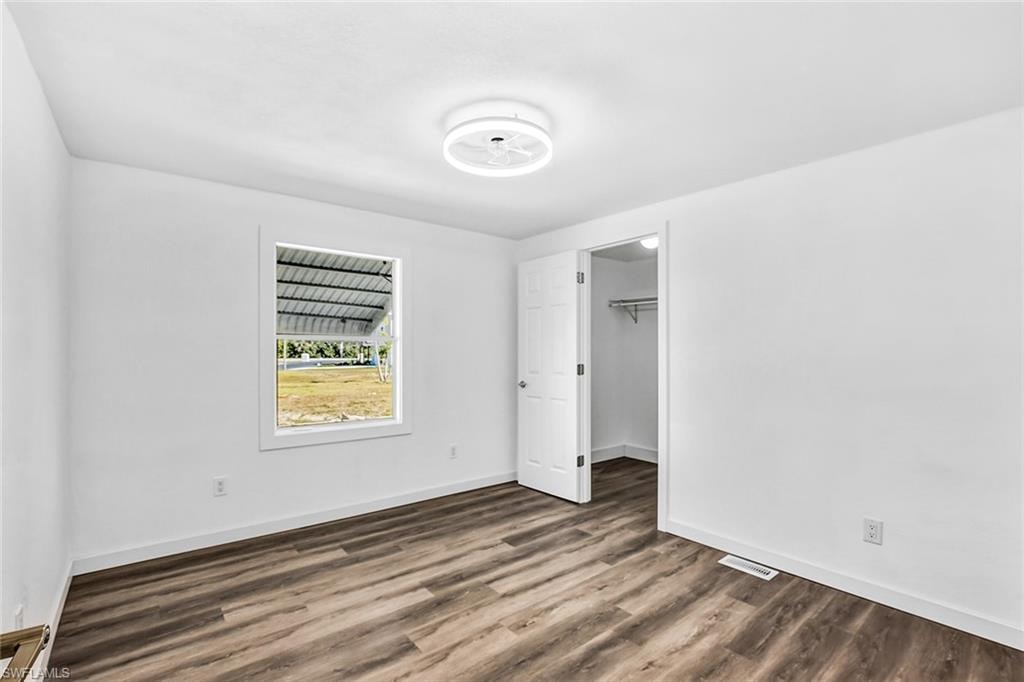 Bright, airy bedroom showcasing wood-finish flooring, white walls, and recessed ceiling lighting