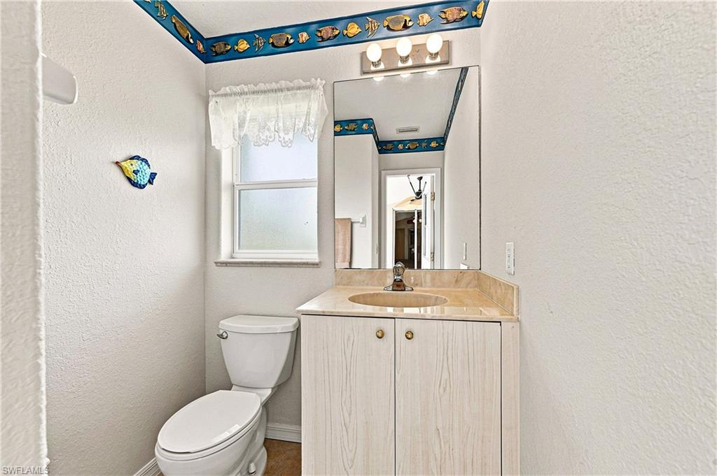 Charming cabana bathroom featuring a vanity with dual cabinet storage, sink, and framed mirror