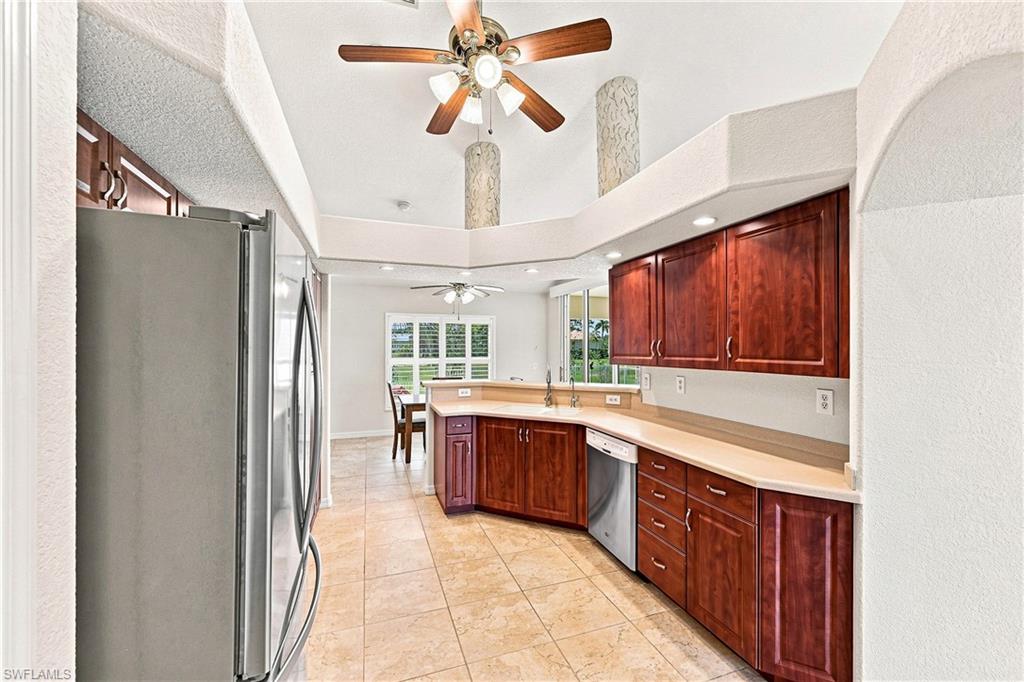 Spacious kitchen featuring rich wood cabinetry, stainless steel appliances including a side-by-side refrigerator, light wood countertops, and tile flooring