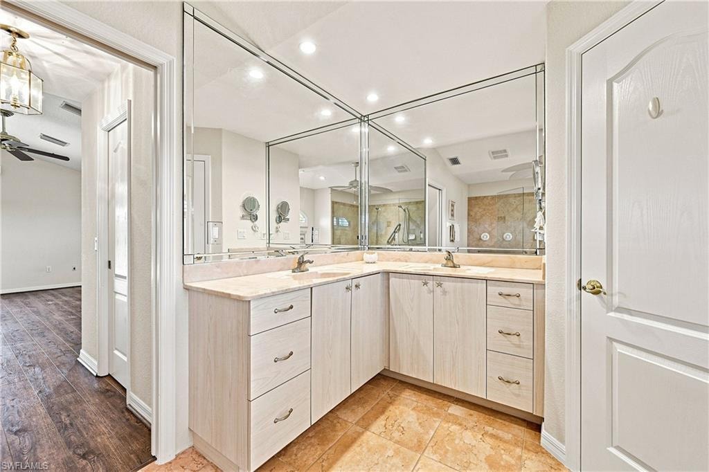 Bathroom featuring a dual vanity with light-toned cabinetry, light-colored countertops, and full-wall mirrors