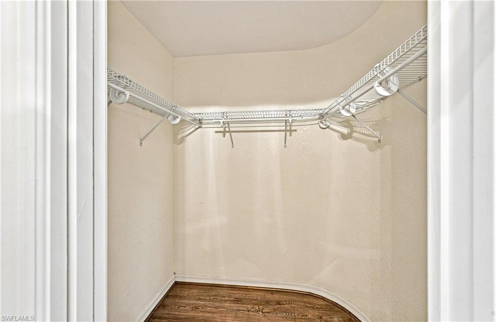 Second walk-in closet featuring wire shelving, hanging rods, and wood-finish flooring